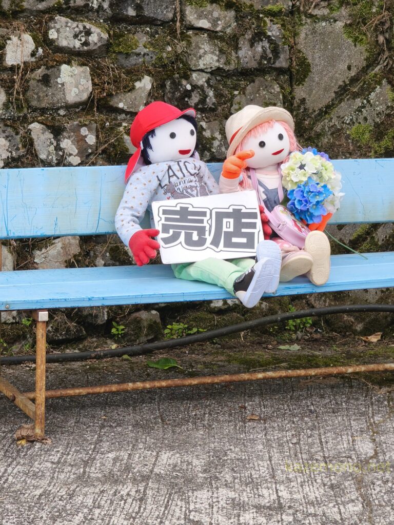 売店案内のボードを持つ布人形