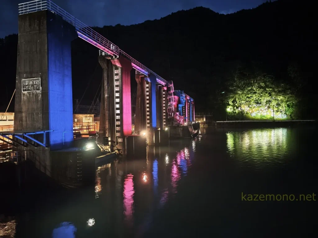 赤と青にライトアップされた夜の川口ダム