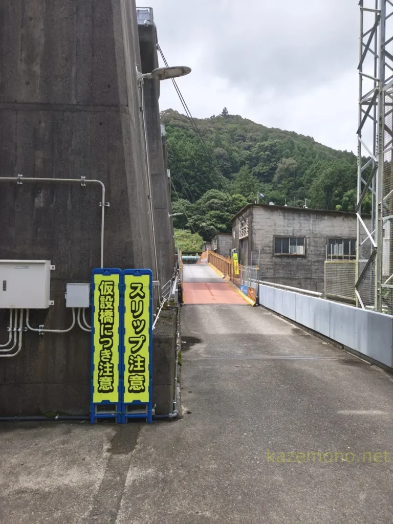 川口ダムの堤体上に設けられた仮設通路と注意看板