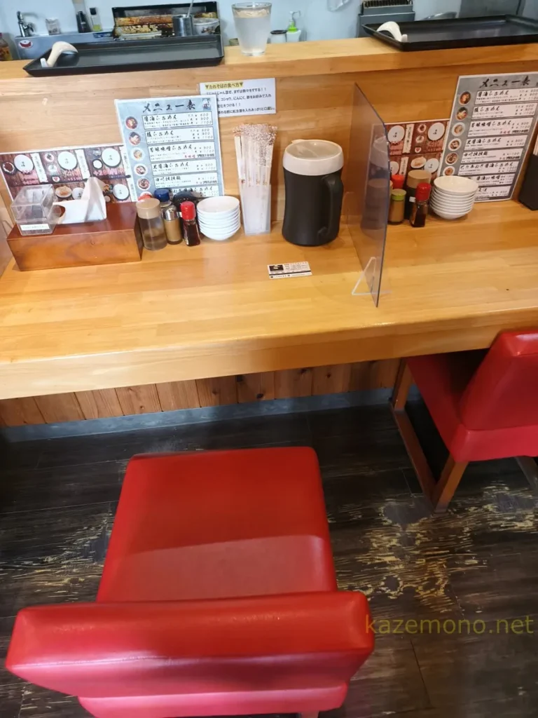 透明な仕切りと調味料が設置された麺屋藤のカウンター席