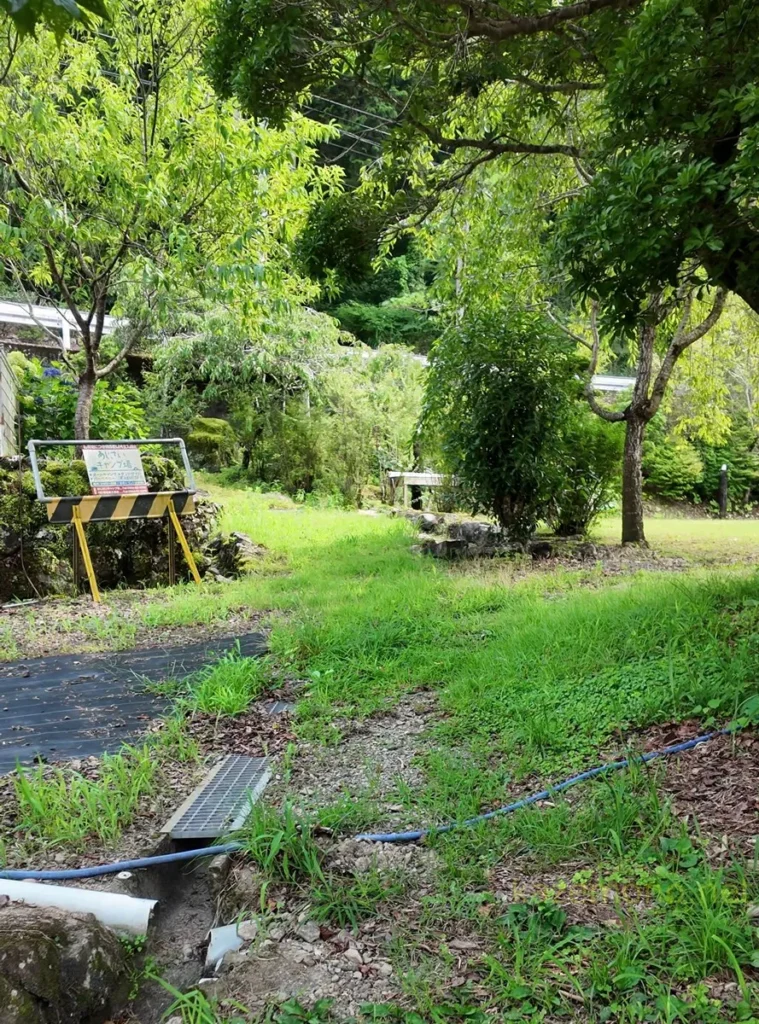 階段の先の道脇に置かれたあじさいキャンプ場の案内板