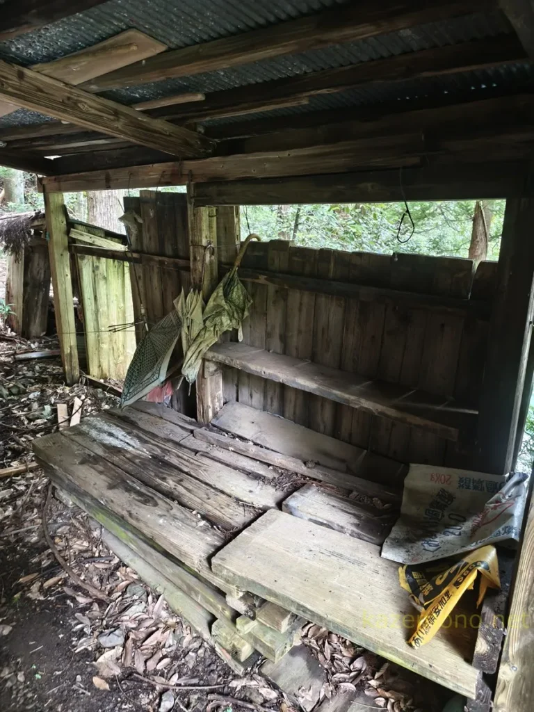 対岸の小屋の屋根下に残る古びた傘と木材