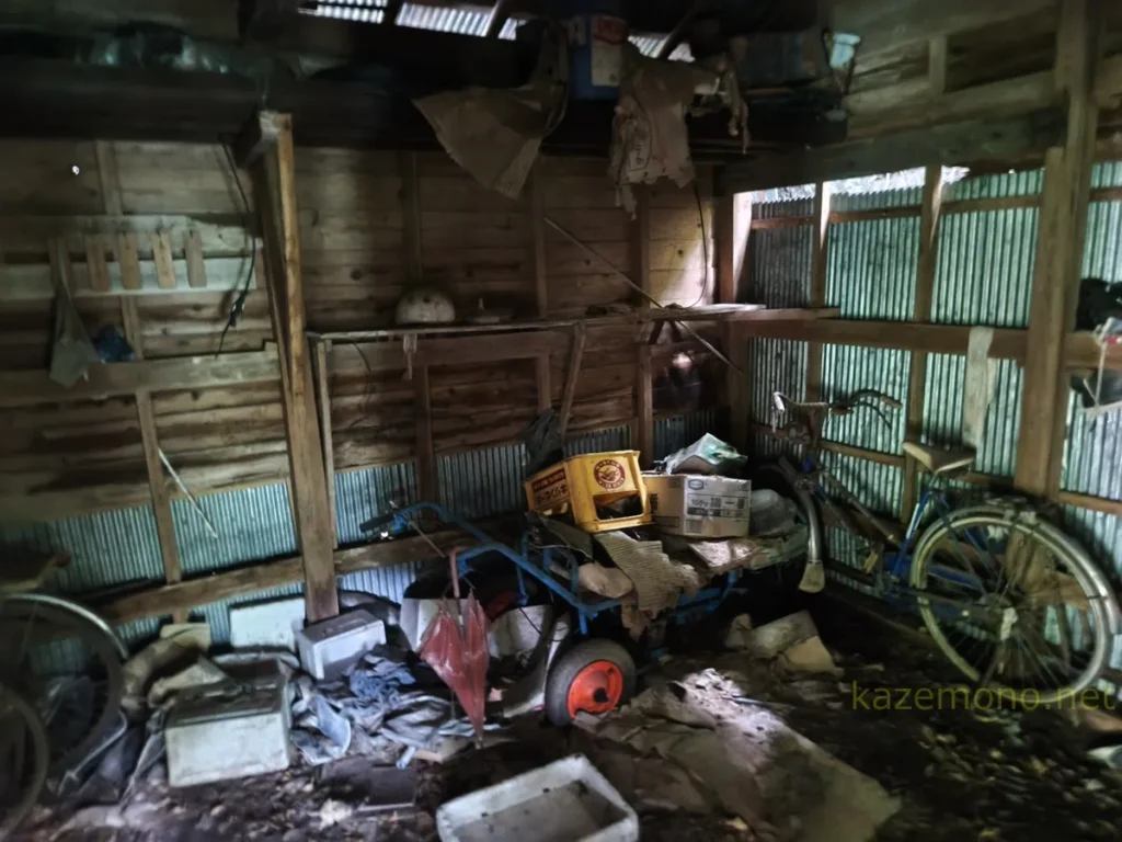 対岸の小屋に残る自転車や手押し車と道具類