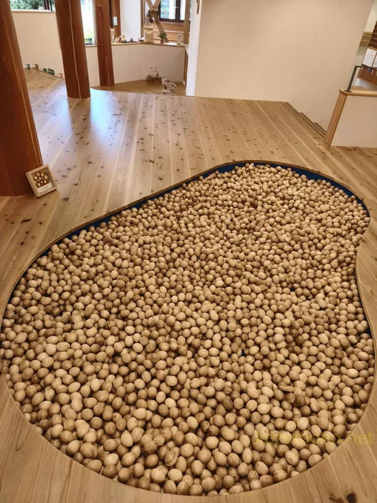 木の卵型ボールが敷き詰められた遊び場