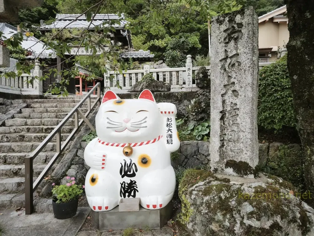 お松大権現の「必勝」と書かれた大きな招き猫と石柱