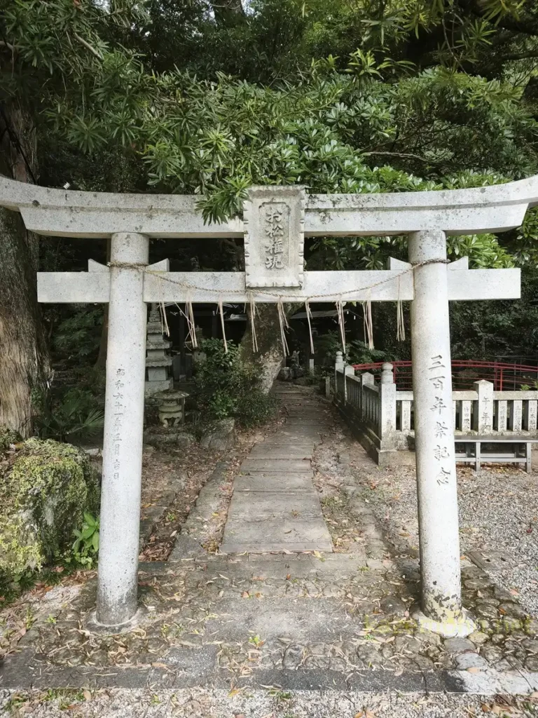 「お松権現」と刻まれた石の鳥居と左奥のお松の墓所